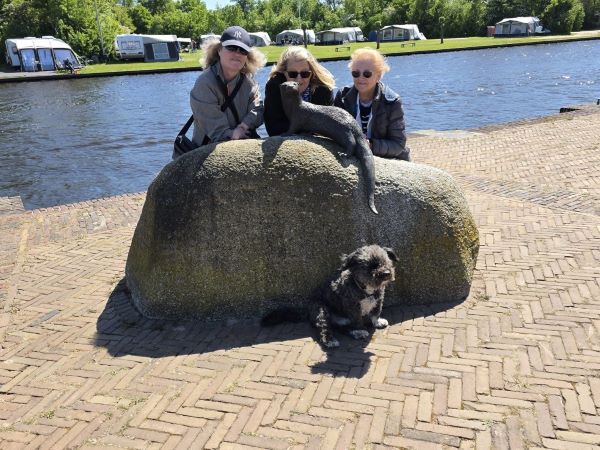 Drei Freundinnen und ein Hund vor der Otterstatue in Earnewald