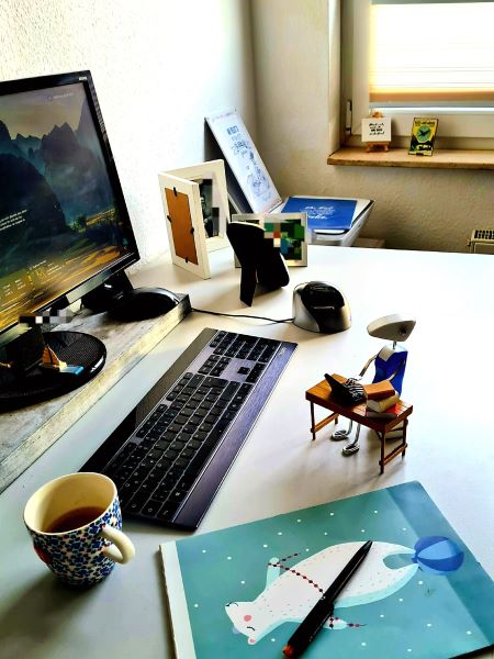 Arbeitsplatz beim Schreiben: Notizblock, PC und Kaffee – aber das Romanprojekt stockt.